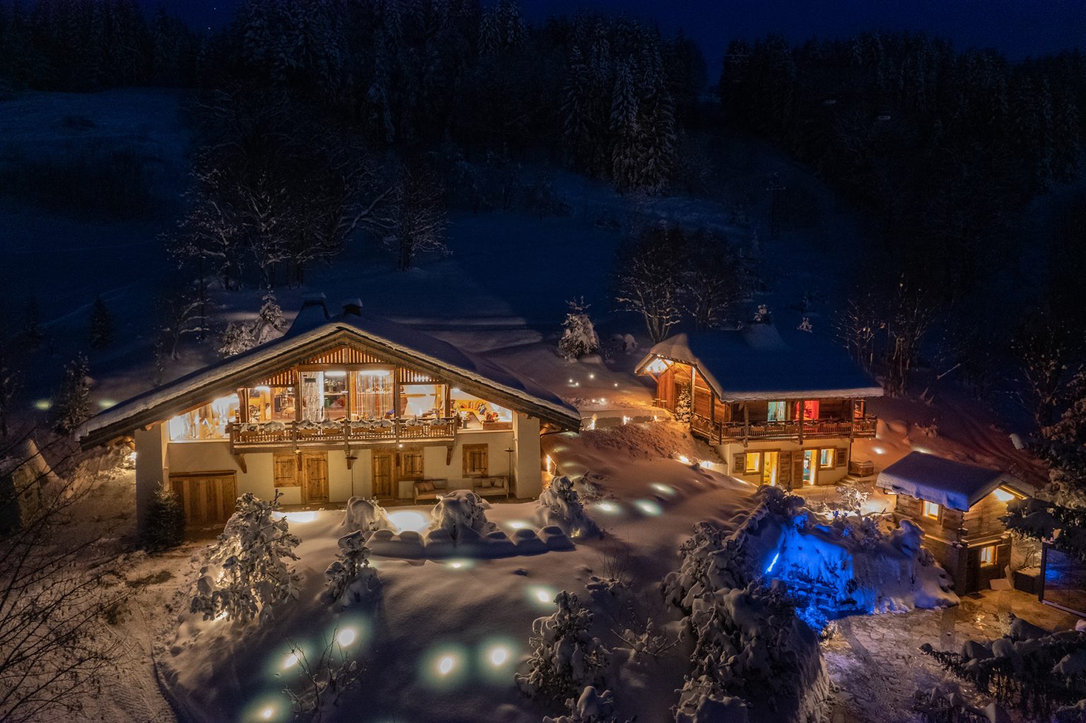 Chalet illuminé sous la neige la nuit