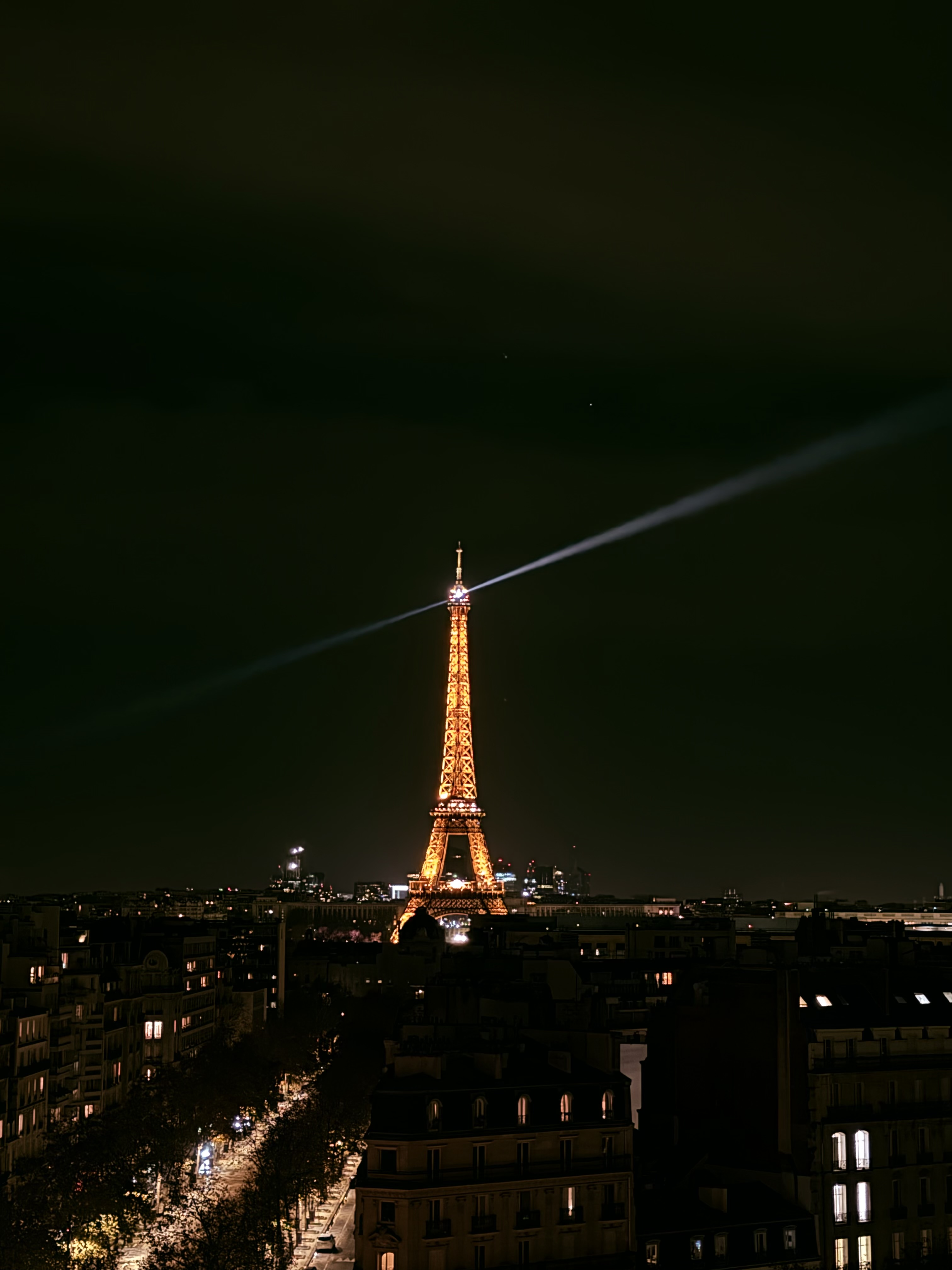 Tour Eiffel illuminée de nuit et son faisceau lumineux sur Paris