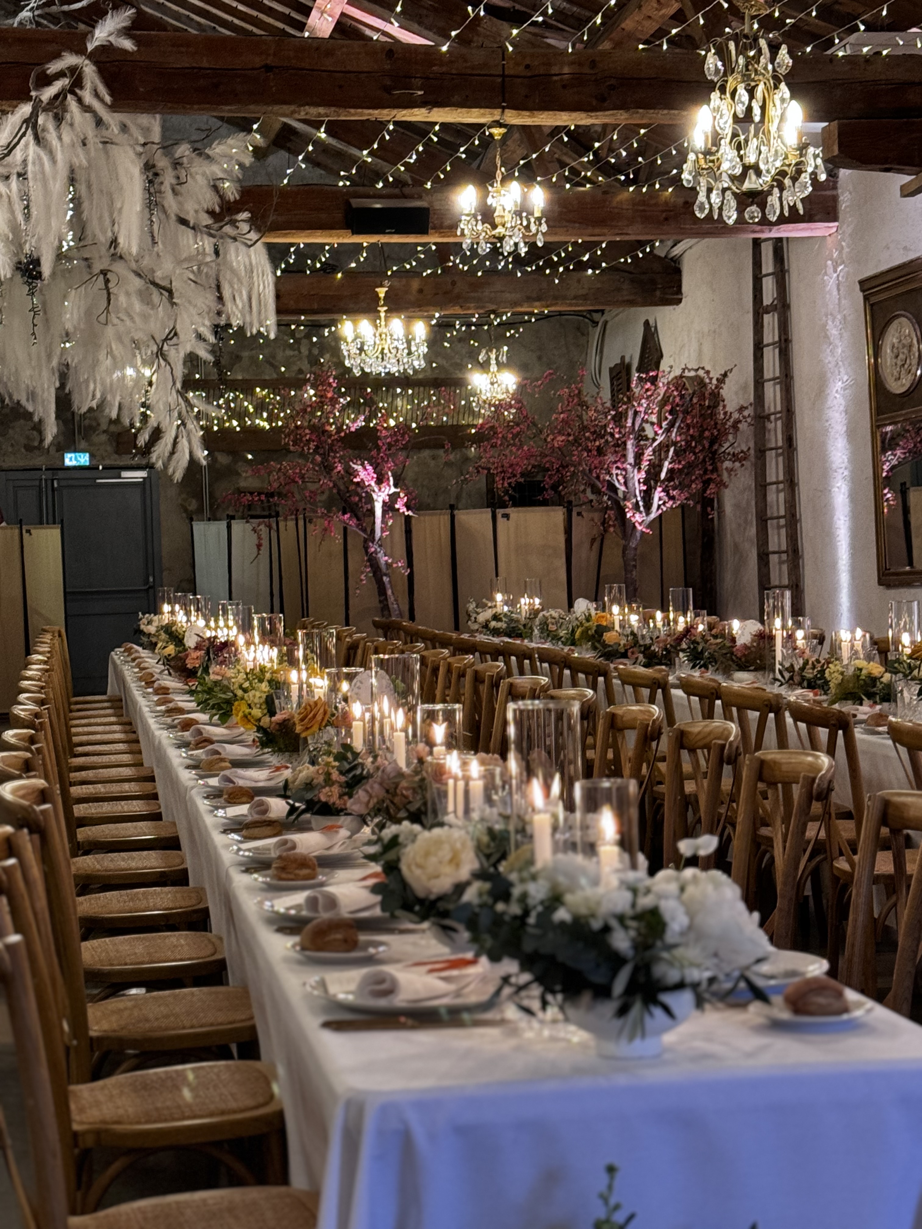 Table de réception dressée sous les poutres et lustres d'une grange d'exception